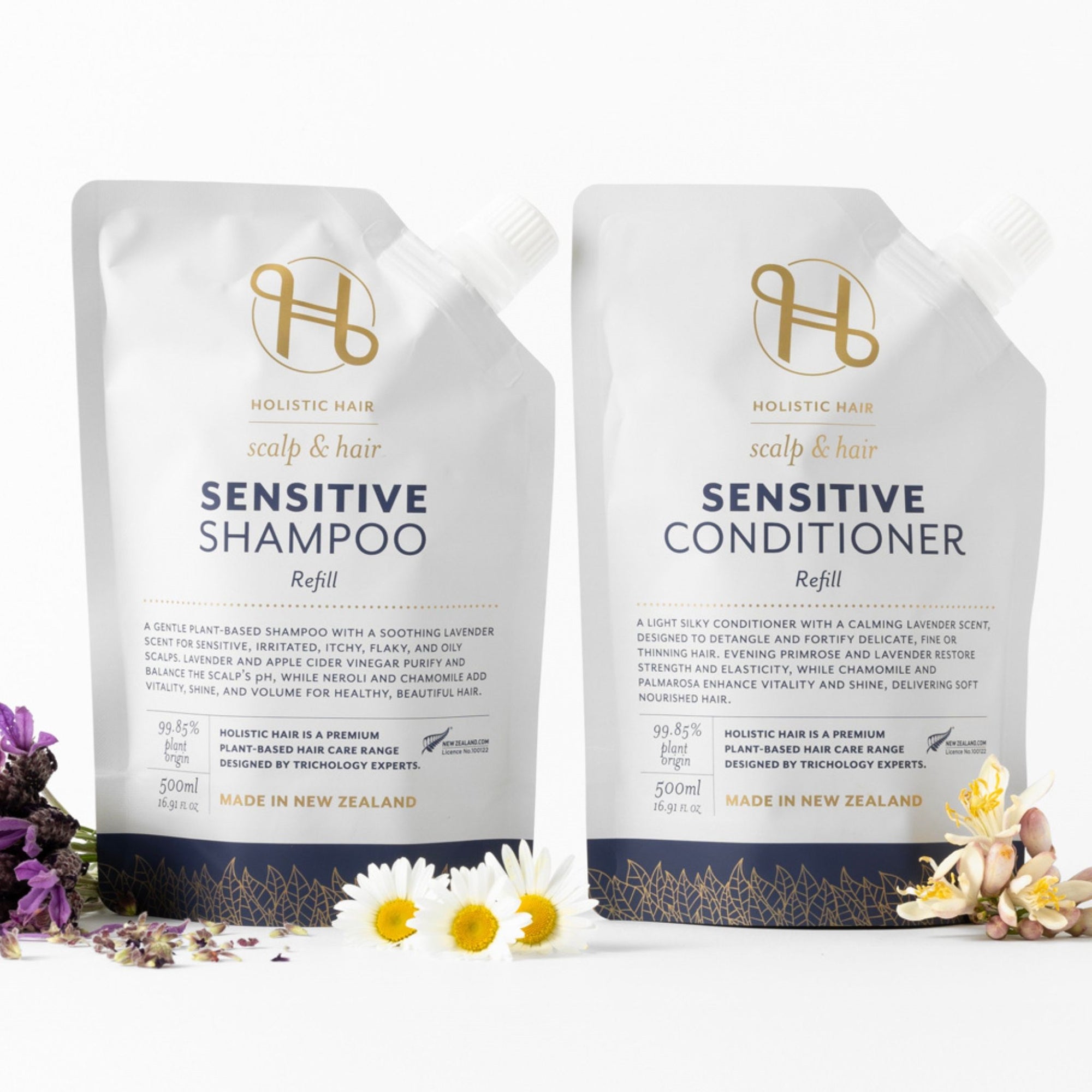 Two Holistic Hair Sensitive Shampoo and Conditioner refill packs on a white background with flowers.